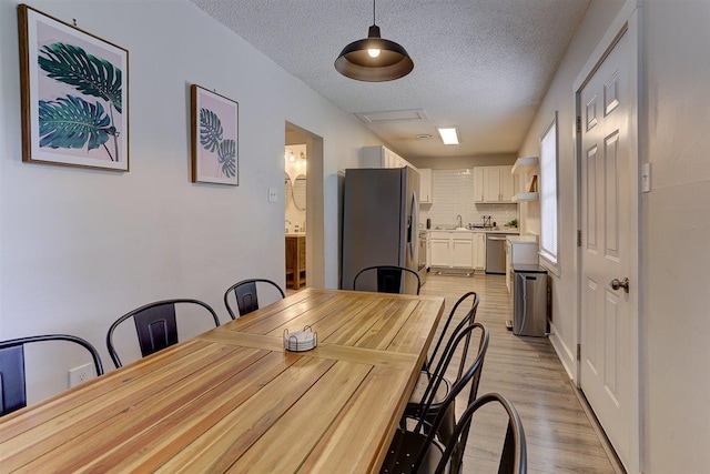 1680 Euclid Ave, Memphis, TN 38114 - dining area featuring a textured ceiling, light wood-style flooring, and attic access