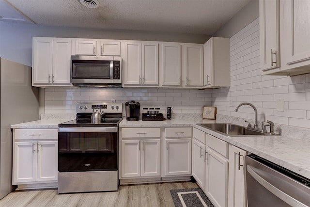 1680 Euclid Ave, Memphis, TN 38114 - kitchen with appliances with stainless steel finishes, light wood-style floors, white cabinetry, and tasteful backsplash