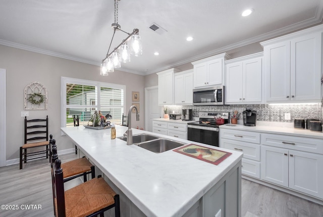 571 Todd Ray Cv, Henderson, TN 38340 - kitchen with appliances with stainless steel finishes, backsplash, light wood-style flooring, an island with sink, and a breakfast bar