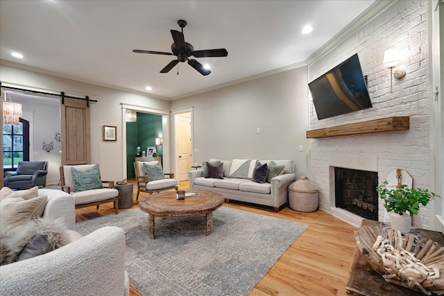 4342 Robinson Loop, Olive Branch, MS 38654 - living room featuring wood finished floors, a barn door, a ceiling fan, ornamental molding, and a large fireplace