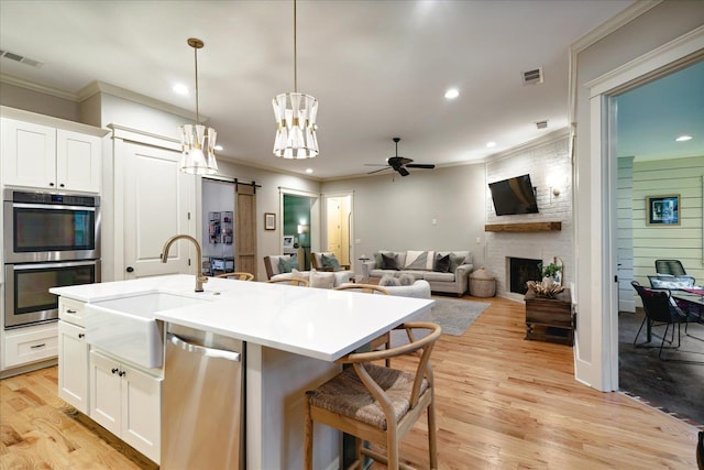 4342 Robinson Loop, Olive Branch, MS 38654 - kitchen featuring stainless steel appliances, crown molding, ceiling fan, a barn door, and a large fireplace