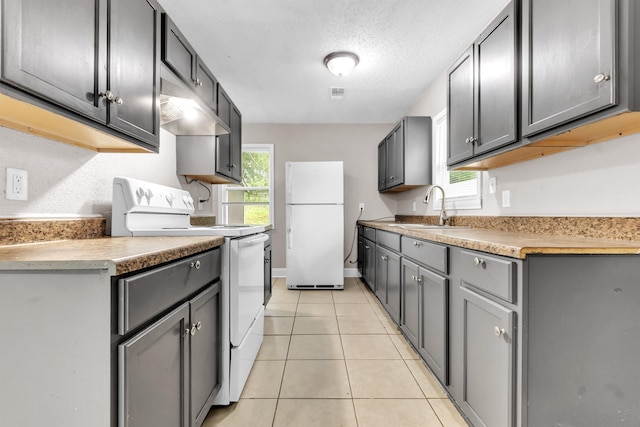 1017 Creston Ave, Memphis, TN 38127 - kitchen with white appliances, light tile patterned floors, under cabinet range hood, gray cabinets, and light countertops