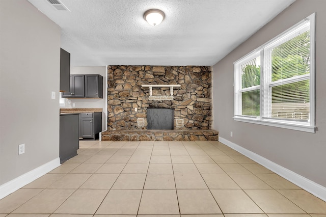 1017 Creston Ave, Memphis, TN 38127 - unfurnished living room with a textured ceiling, a fireplace, and light tile patterned floors