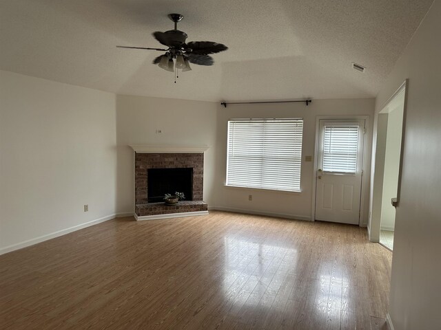 992 Zenith Cv N, Unicorp/Memphis, TN 38018 - unfurnished living room with wood finished floors, ceiling fan, lofted ceiling, a fireplace, and a textured ceiling