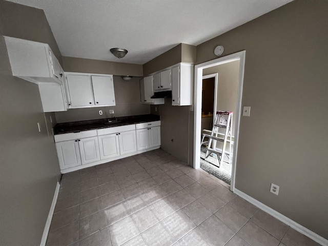 3402 Dungreen Dr, Memphis, TN 38118 - kitchen featuring light tile patterned floors, dark countertops, and white cabinetry