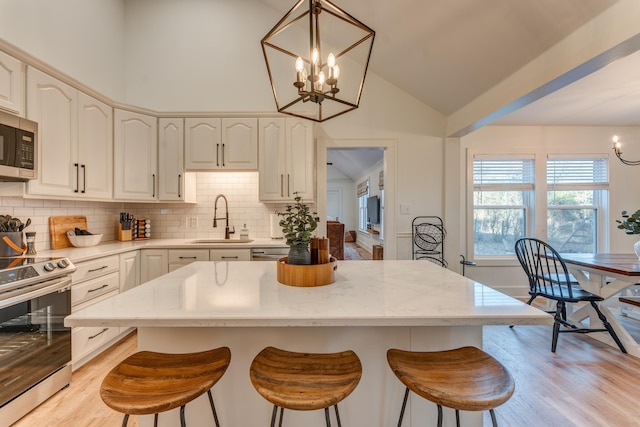 4950 Yum Yum Rd, Somerville, TN 38068 - kitchen featuring appliances with stainless steel finishes, a chandelier, a breakfast bar area, light wood-style flooring, and backsplash