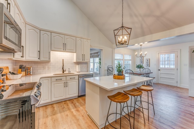 4950 Yum Yum Rd, Somerville, TN 38068 - kitchen with appliances with stainless steel finishes, a chandelier, a breakfast bar area, light wood-style floors, and decorative backsplash