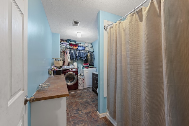 1635 Norton Rd, Middleton, TN 38052 - bathroom featuring washer and dryer, a textured ceiling, curtained shower, and a walk in closet