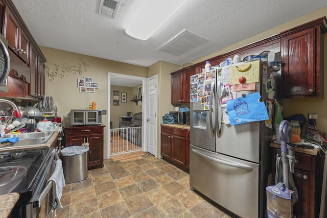 1635 Norton Rd, Middleton, TN 38052 - kitchen featuring stainless steel appliances, stone finish floors, reddish brown cabinets, a textured ceiling, and light countertops