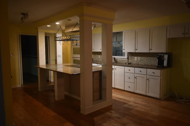 101 Bob St, Selmer, TN 38375 - kitchen featuring recessed lighting, white cabinetry, dark wood-style flooring, backsplash, and multiple ovens