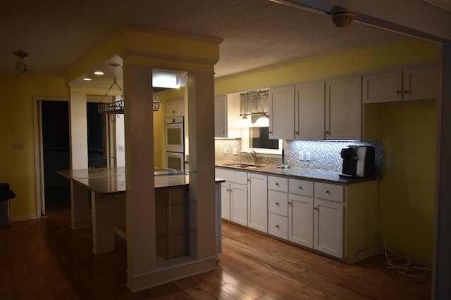 101 Bob St, Selmer, TN 38375 - kitchen featuring wood finished floors, double oven, backsplash, white cabinets, and a center island