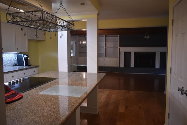 101 Bob St, Selmer, TN 38375 - kitchen featuring black electric stovetop, wood finished floors, white cabinetry, stone countertops, and a fireplace