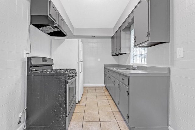 3205 E Shirley Cir, Memphis, TN 38127 - kitchen with gas stove, tile walls, gray cabinetry, wall chimney range hood, and light tile patterned flooring