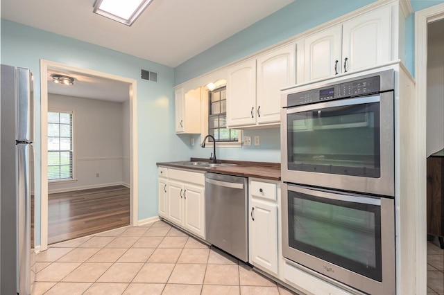 2539 Kenwood Rd, Bartlett, TN 38134 - kitchen with appliances with stainless steel finishes, light tile patterned floors, wood counters, and white cabinets