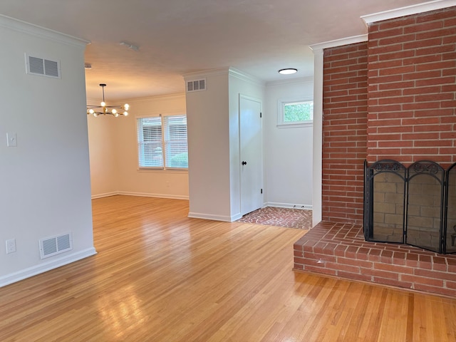 3652 Acacia St, Memphis, TN 38116 - unfurnished living room with light wood-style flooring, crown molding, a brick fireplace, and a chandelier