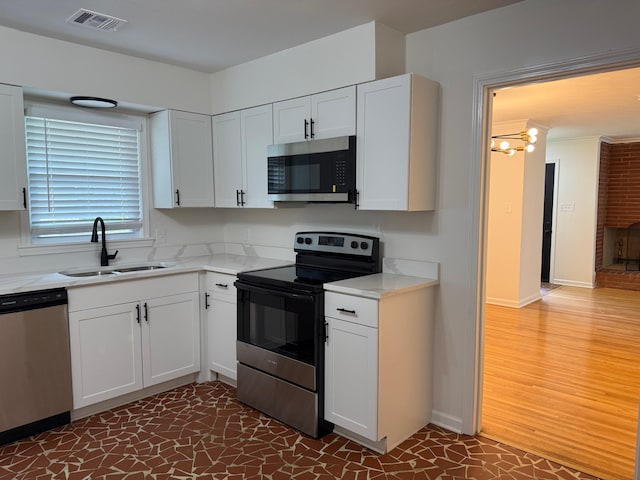 3652 Acacia St, Memphis, TN 38116 - kitchen with stainless steel appliances, light countertops, white cabinetry, dark wood-style floors, and a chandelier