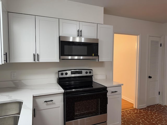 3652 Acacia St, Memphis, TN 38116 - kitchen featuring electric range, stainless steel microwave, white cabinetry, and light stone countertops