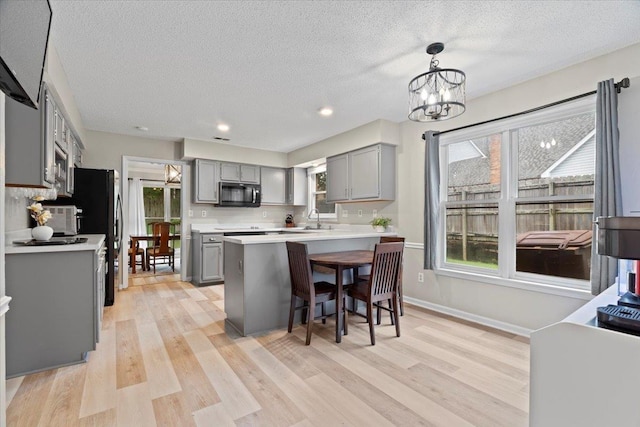 3077 Stonecrest Cir E, Lakeland, TN 38002 - kitchen featuring gray cabinetry, black microwave, light wood-style flooring, light countertops, and a chandelier