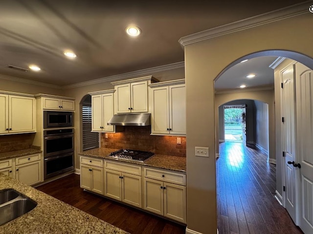 10040 Dropseed Cir, Lakeland, TN 38002 - kitchen featuring arched walkways, under cabinet range hood, appliances with stainless steel finishes, stone countertops, and crown molding