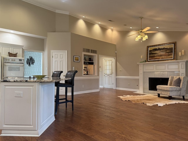 7598 Fairway Forest Dr E, Memphis, TN 38016 - kitchen featuring white oven, crown molding, a breakfast bar area, dark wood finished floors, and light stone counters