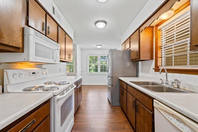 6864 Aspenhill Dr, Bartlett, TN 38135 - kitchen featuring white appliances, a textured ceiling, light countertops, dark wood-style flooring, and brown cabinetry