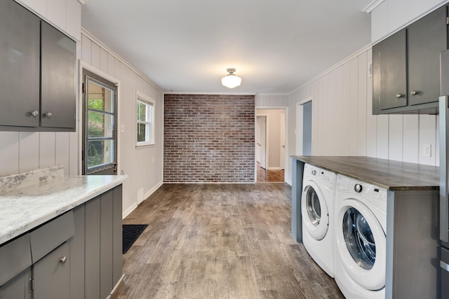 3218 Joffre Ave, Memphis, TN 38111 - washroom featuring washing machine and dryer, ornamental molding, brick wall, dark wood finished floors, and cabinet space