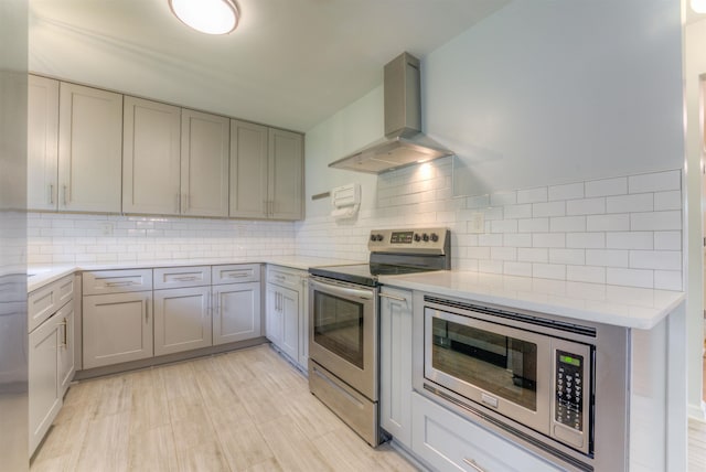 4427 Quince Rd, Memphis, TN 38117 - kitchen with appliances with stainless steel finishes, wall chimney range hood, gray cabinets, and decorative backsplash