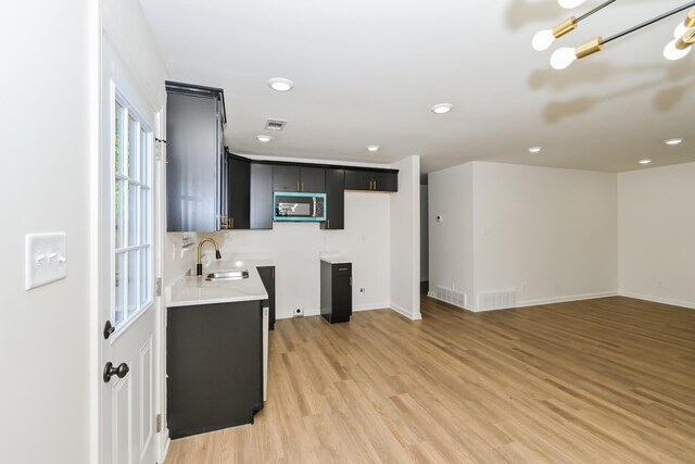 4130 Cottonwood Rd, Memphis, TN 38118 - kitchen with stainless steel microwave, dark cabinets, light wood-style flooring, light countertops, and recessed lighting