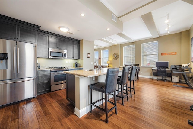 127 Madison Ave Unit 602, Memphis, TN 38103 - kitchen with stainless steel appliances, light stone countertops, dark wood-type flooring, a breakfast bar area, and a center island with sink