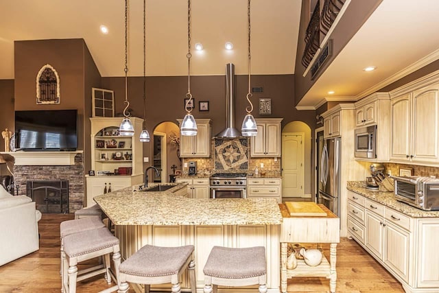 190 Links View Dr, Oakland, TN 38060 - kitchen featuring stainless steel appliances, arched walkways, light wood-type flooring, a stone fireplace, and a high ceiling