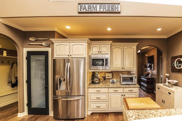 190 Links View Dr, Oakland, TN 38060 - kitchen with appliances with stainless steel finishes, arched walkways, cream cabinetry, dark wood-type flooring, and crown molding