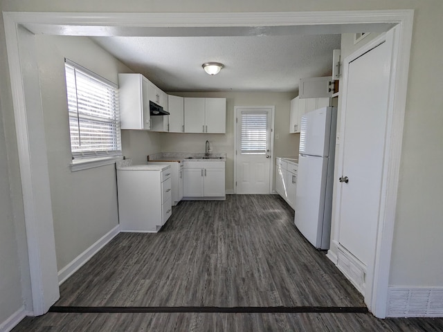 4499 Range Line Rd, Memphis, TN 38127 - kitchen featuring freestanding refrigerator, under cabinet range hood, dark wood finished floors, white cabinets, and a textured ceiling