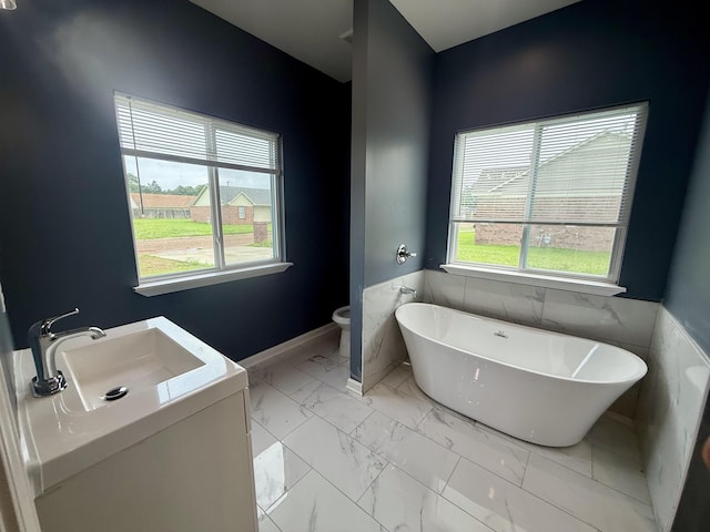 32 Foxchase Dr, Mason, TN 38049 - bathroom featuring a soaking tub, marble look tile flooring, vanity, and a wainscoted wall