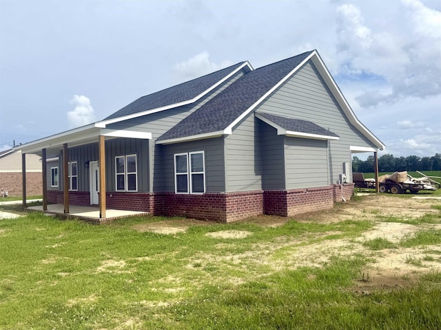 32 Foxchase Dr, Mason, TN 38049 - view of side of property with a shingled roof, brick siding, a patio, a yard, and board and batten siding