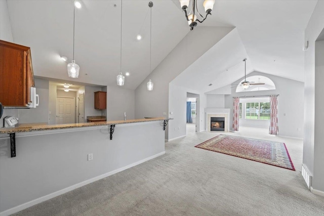 8897 Parkview Oaks Cir, Olive Branch, MS 38654 - kitchen with vaulted ceiling, carpet flooring, brown cabinetry, pendant lighting, and a lit fireplace