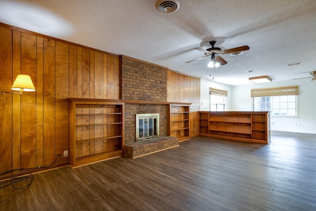 5662 Chapman Ave, Memphis, TN 38119 - unfurnished living room with a ceiling fan, dark wood-type flooring, a textured ceiling, wood walls, and a brick fireplace