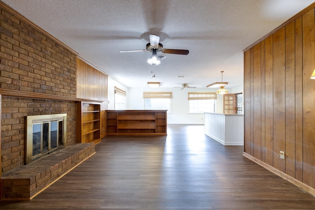 5662 Chapman Ave, Memphis, TN 38119 - unfurnished living room featuring ceiling fan, a textured ceiling, wooden walls, dark wood finished floors, and a brick fireplace
