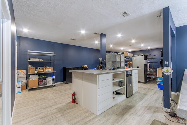 119 N 4th St, Selmer, TN 38375 - kitchen with light wood-style floors, open shelves, light countertops, a textured ceiling, and a kitchen island