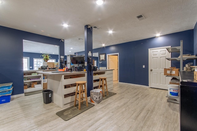 119 N 4th St, Selmer, TN 38375 - kitchen featuring light wood-style flooring, a textured ceiling, a kitchen bar, a kitchen island, and recessed lighting