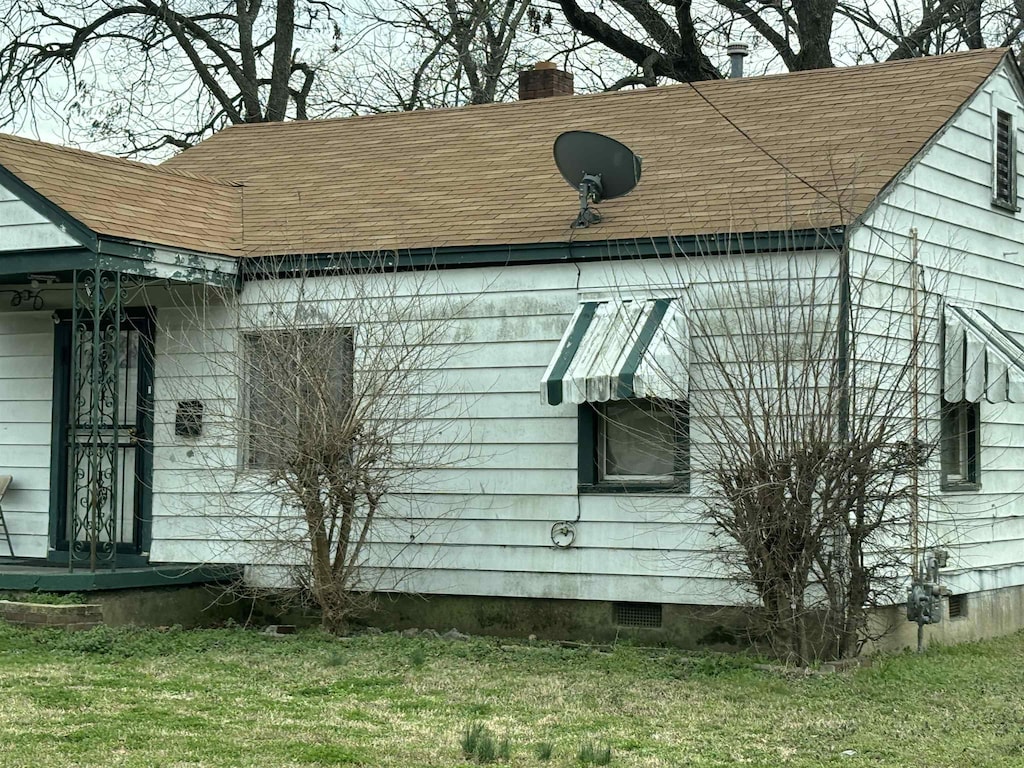 1983 Hubert Ave, Memphis, TN 38108 - view of side of property with crawl space, a shingled roof, a chimney, and a yard