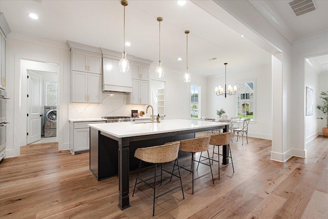 2486 E Allelon Rd E, Germantown, TN 38138 - kitchen with crown molding, washer / clothes dryer, light wood-type flooring, a breakfast bar area, and recessed lighting