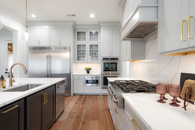 2486 E Allelon Rd E, Germantown, TN 38138 - kitchen with custom exhaust hood, stainless steel appliances, pendant lighting, light wood-style floors, and light stone counters