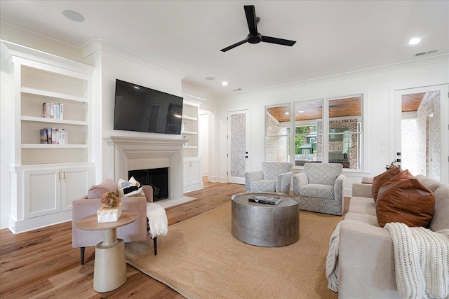 2486 E Allelon Rd E, Germantown, TN 38138 - living room featuring ornamental molding, ceiling fan, wood finished floors, a fireplace with raised hearth, and built in shelves