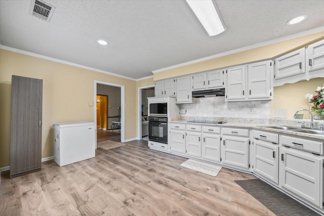 3889 Oak Trace Cv, Bartlett, TN 38135 - kitchen with black appliances, under cabinet range hood, a textured ceiling, ornamental molding, and tasteful backsplash