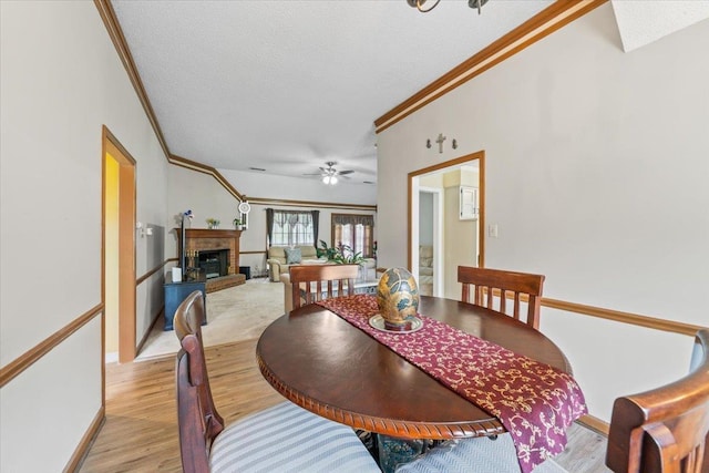 3889 Oak Trace Cv, Bartlett, TN 38135 - dining space featuring crown molding, light wood-style floors, a textured ceiling, a fireplace, and a ceiling fan