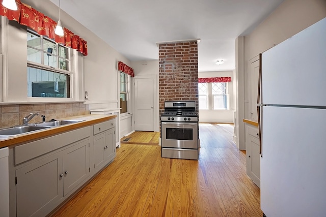 2067 Hallwood Dr, Memphis, TN 38107 - kitchen with freestanding refrigerator, gas stove, light wood-style flooring, and tasteful backsplash