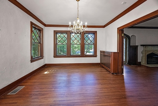 2067 Hallwood Dr, Memphis, TN 38107 - unfurnished dining area featuring wood finished floors, a chandelier, a textured wall, ornamental molding, and a fireplace with flush hearth