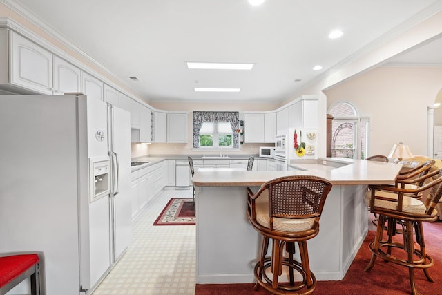 6500 State Line Rd, Tn, TN 38141 - kitchen featuring white appliances, a kitchen bar, a peninsula, crown molding, and light countertops