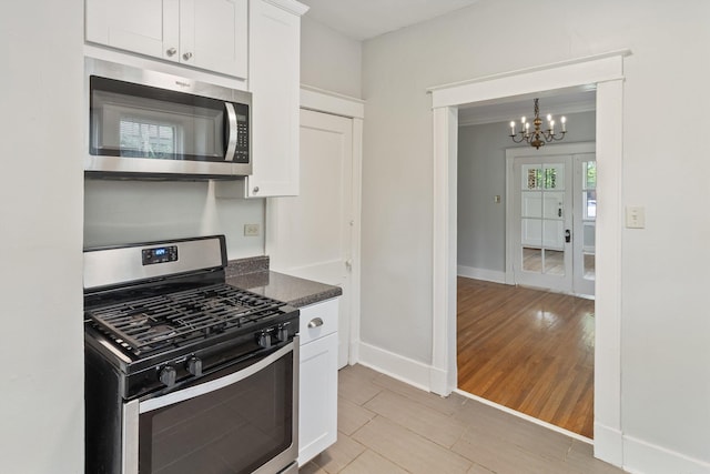 730 Maury St, Memphis, TN 38107 - kitchen featuring stainless steel appliances, a chandelier, white cabinets, and light wood finished floors