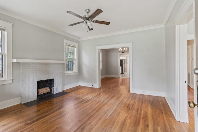730 Maury St, Memphis, TN 38107 - unfurnished living room featuring a brick fireplace, wood-type flooring, a ceiling fan, ornamental molding, and a chandelier